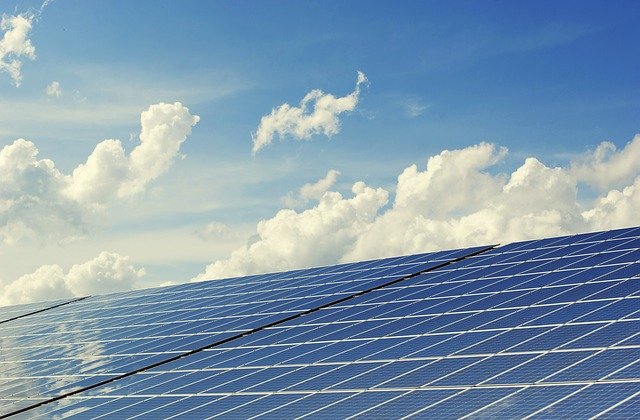 Das Foto zeigt eine Solarfläche und blauen Himmel mit weißen Wolken.